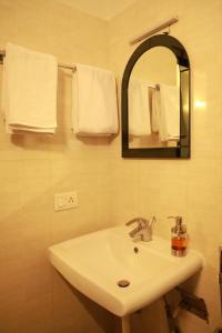 班加罗尔ZIONS AIRPORT HOTEL AND APERTMENT! Near Kempegowda International Airport的浴室配有盥洗盆、镜子和毛巾