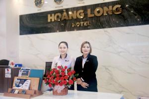 潘切Hoang Long Hotel Phan Thiết的两个女人站在桌子旁边,花瓶
