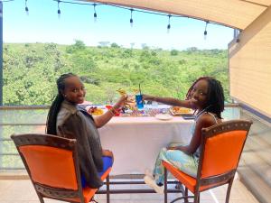 内罗毕Olsupat Lodge的两个坐在桌子边吃食物的女孩