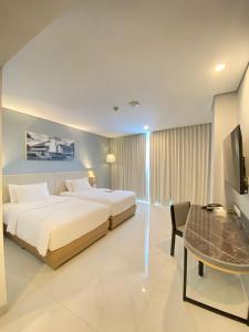 玛琅OJ玛琅1O1酒店的一间卧室配有两张床、一张桌子和一台电视。