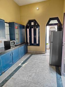 AyodhyaShantiniketan 4BHK Comfortable Family Stay in Ayodhya的厨房配有蓝色橱柜和冰箱。
