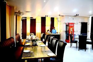 AyodhyaTaraji Resort Hotel & Restaurant Ayodhya的一间用餐室,配有一张长桌子和椅子,后面还有一位男士
