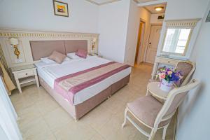 马马亚苏利纳国际酒店的一间卧室配有一张大床和一把椅子