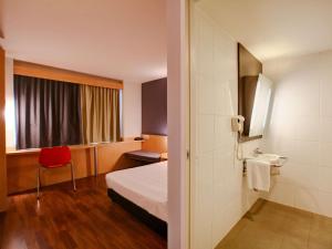 里约热内卢里约热内卢宜必思巴拉达蒂茹卡酒店的酒店客房,配有一张床和一张红色椅子