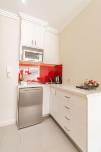 悉尼Best Western Plus Camperdown Suites的一间厨房,配有白色的橱柜和红色的点缀