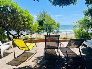 泰拉奇纳Villa GREG stupenda location sulla spiaggia con accesso diretto al mare的三把椅子和一张桌子,后面是海滩