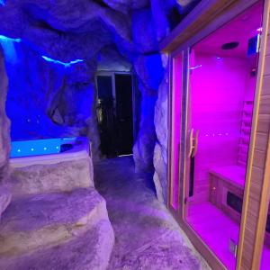 那不勒斯Napoli Centro Suite e Spa的一间设有岩石洞穴、粉红色和蓝色灯光的客房