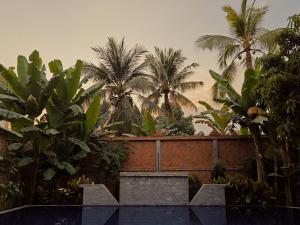 暹粒Angkor Sand Hotel的一座种有棕榈树和砖墙的花园