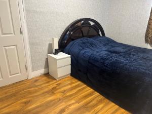 伦敦London Holiday Home的一间卧室配有一张带蓝色毯子和床头柜的床