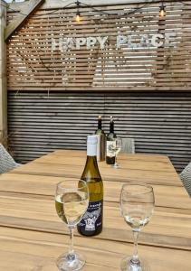 谢林汉姆Happy Place, Sheringham Stunner - Crabpot Cottages Sheringham的桌子上放有一瓶葡萄酒和两杯酒