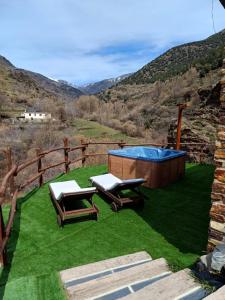 特雷韦莱斯Casa Rural Cortijo Molino Altero的后院设有热水浴池和2把躺椅