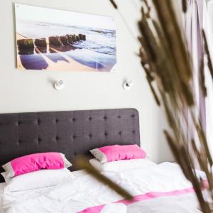 姆热日诺泽瑞佳公寓酒店的一间卧室配有带粉红色枕头的床和床头板
