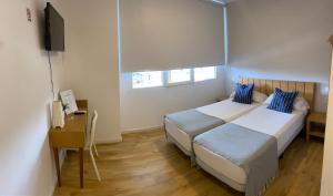 瓦伦西亚Nanit Valencia Hostel的一间卧室配有两张床、一张桌子和一台电视。