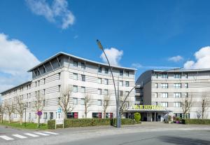 科凯勒B&B HOTEL Calais Terminal Cité Europe 3 étoiles的上面有旗帜的白色建筑