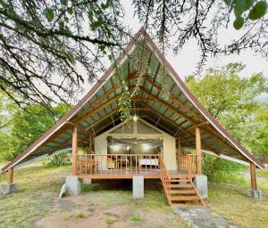 OlolaimutiekMara Empiris Safari Camp的茅草屋顶房屋,配有桌椅