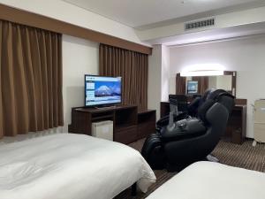 米子市Hotel Alpha-One Yonago的酒店客房配有一张床、一把椅子和一台电视。