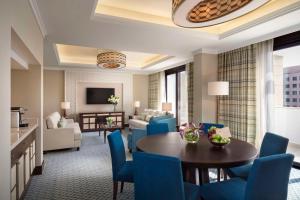 多哈Al Najada Doha Hotel by Tivoli的客厅配有桌子和蓝色椅子