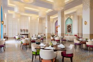 多哈Al Najada Doha Hotel by Tivoli的一间在房间内配有桌椅的餐厅