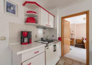 魏申费尔德Haus Wiesenttal的厨房配有白色橱柜和红色用具