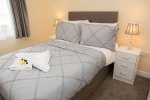 斯特劳德White Jasmine In Stroud的一间卧室配有一张带灰色棉被和枕头的床