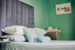 温特和克Kate's Nest Guesthouse的一间卧室设有绿色的墙壁和一张带枕头的床