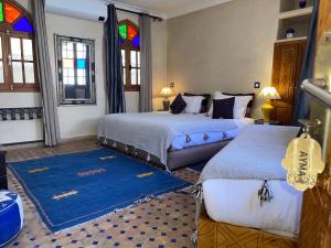 塔鲁丹特塔菲拉格摩洛哥传统庭院住宅的一间卧室设有两张床和彩色玻璃窗。