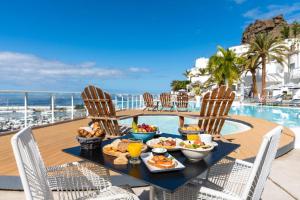 波多黎各大加那利岛海湾景码头公寓 - 仅限成人入住的一张桌子,旁边是游泳池,摆放着食物和饮料