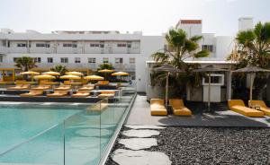 科拉雷侯Buendía Corralejo nohotel的一座设有游泳池、椅子和遮阳伞的酒店