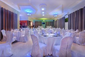 MbuguniNew Mazubu Grand Hotel Mererani的宴会厅配有白色的桌子和白色的椅子