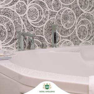 GjakoveHotel Apollonia的浴室设有白色水槽和黑白壁纸。