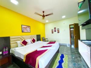 普里Goroomgo Coral Suites Puri Near Sea Beach with Swimming Pool - Parking Facilities的一间卧室设有一张黄色墙壁的大床