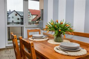 库瑞尼卡慕斯卡Flatbook Apartamenty - Krynica Morska Gdańska的餐桌,带盘子和花瓶