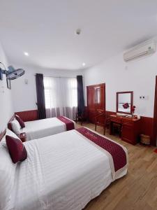 岘港Quốc Khánh Hotel Da Nang的酒店客房设有三张床和一张书桌