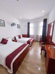 岘港Quốc Khánh Hotel Da Nang的酒店客房配有两张床和一张书桌