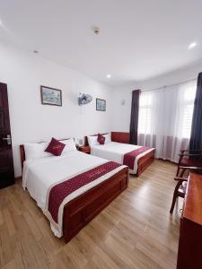 岘港Quốc Khánh Hotel Da Nang的一间卧室配有两张床和一张桌子
