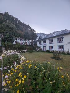 LuklaLukla Himalaya Lodge的一座白色的大建筑,在院子里种着鲜花