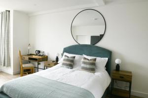 Woburn SandsThe Almshouse Suites的一间卧室配有一张大床,上面有镜子