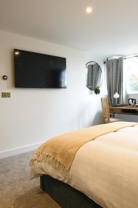 Woburn SandsThe Almshouse Suites的卧室配有一张壁挂式平面电视的床。
