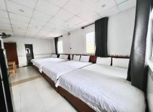 头顿Hoài Thu Hotel Vũng Tàu的白色墙壁的房间的一排床位