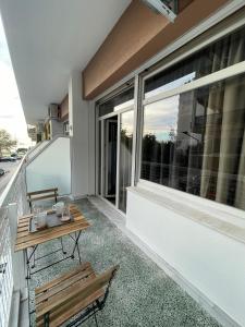 塞萨洛尼基PANSEA 15 IsimeriaHomz的阳台设有长凳、桌子和窗户。