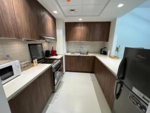 沙迦Cozy beautiful apartment Al zahia mall的厨房配有木制橱柜和黑色冰箱。