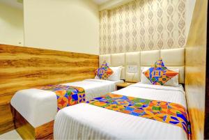 孟买Wind Flower Hotel New Aadya International Near International Airport的酒店客房,配有两张带彩色床单的床