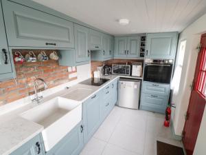 恩尼斯克朗Freemans Cottage的厨房配有蓝色橱柜和砖墙