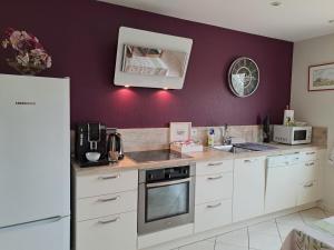 ArdevonB&B La Rive - Le Mont Saint Michel的厨房配有白色橱柜和紫色墙壁