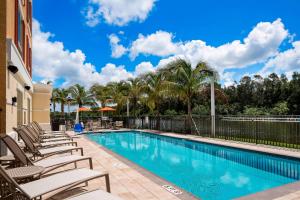 埃斯特罗TownePlace Suites by Marriott Fort Myers Estero的一个带躺椅的游泳池,棕榈树