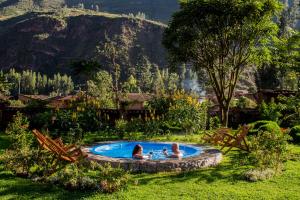 库斯科Lamay Lodge的两人坐在花园里的游泳池里