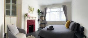 伦敦Modern four bedroom semi-detached house with off street parking 8 min drive to Wembley stadium, 5 miles to Central London的一间卧室配有一张床、一把椅子和一个壁炉