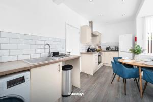 EtruriaNEW Stanley House - Stunning 2 Bedroom House的厨房配有水槽和一张带蓝色椅子的桌子