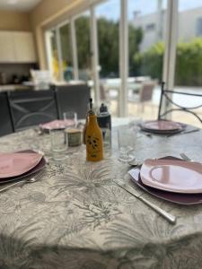 尼姆Maison de famille avec clim, piscine et parking的一张桌子上放着粉色的盘子和黄色的瓶子