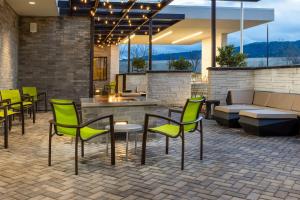 普莱森顿SpringHill Suites by Marriott Pleasanton的一个带绿色椅子和沙发的庭院